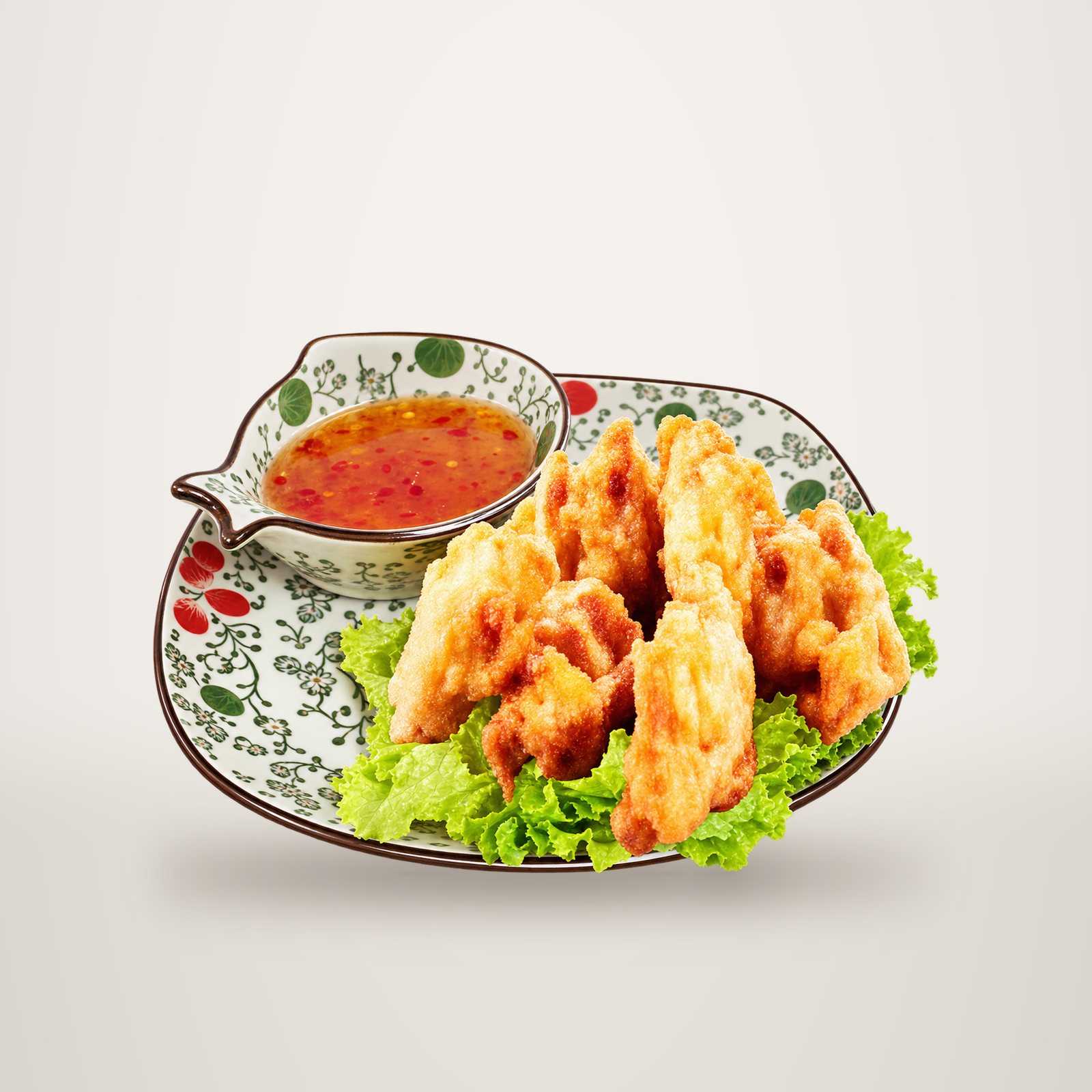 Assiette ornée de motifs floraux garnie de salade verte et de beignets dorés, accompagnés d'un petit bol de sauce aigre-douce orangée.