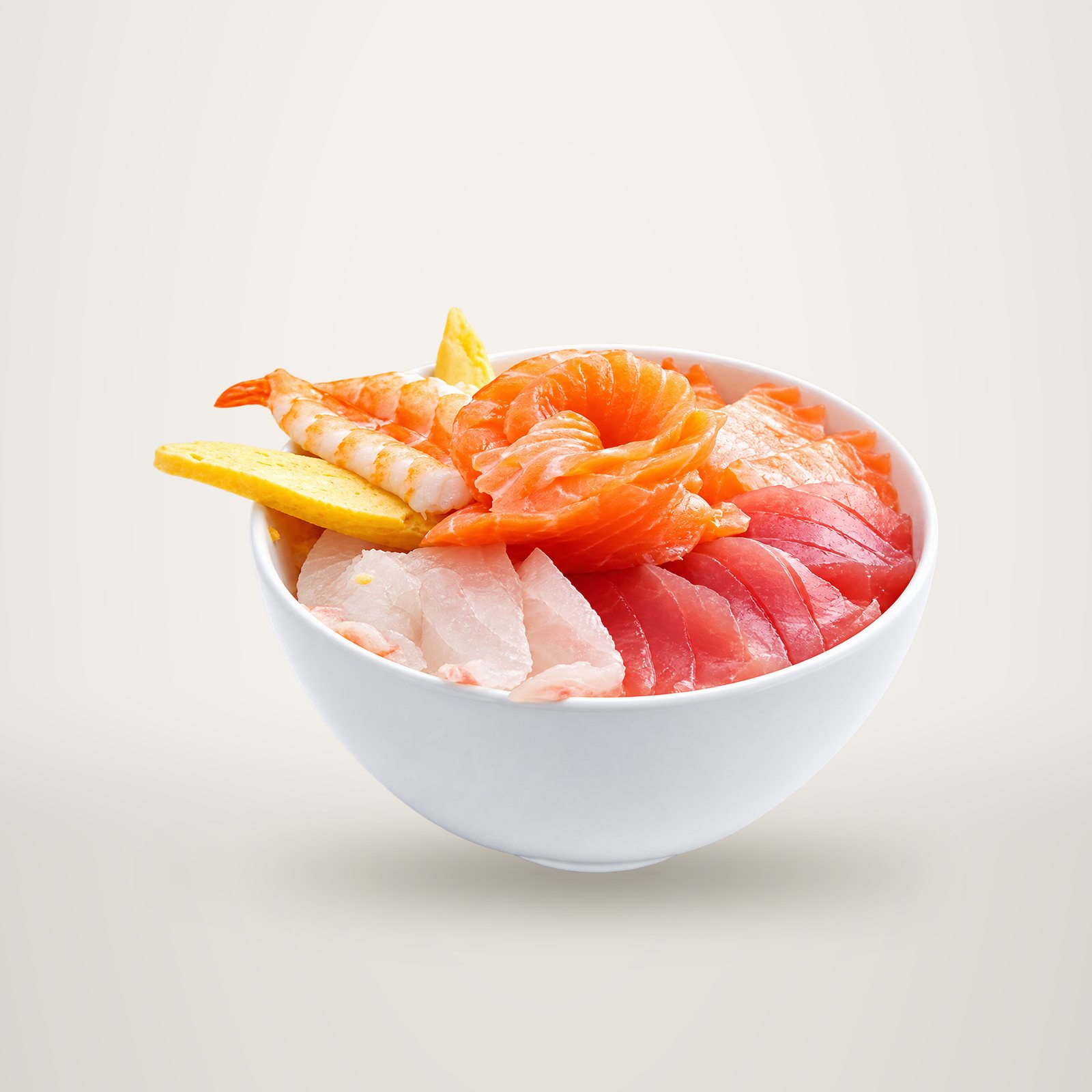 Un bol blanc garni de tranches de saumon, de thon, de poisson blanc, d'une crevette et de mangue, photographié sur fond blanc.