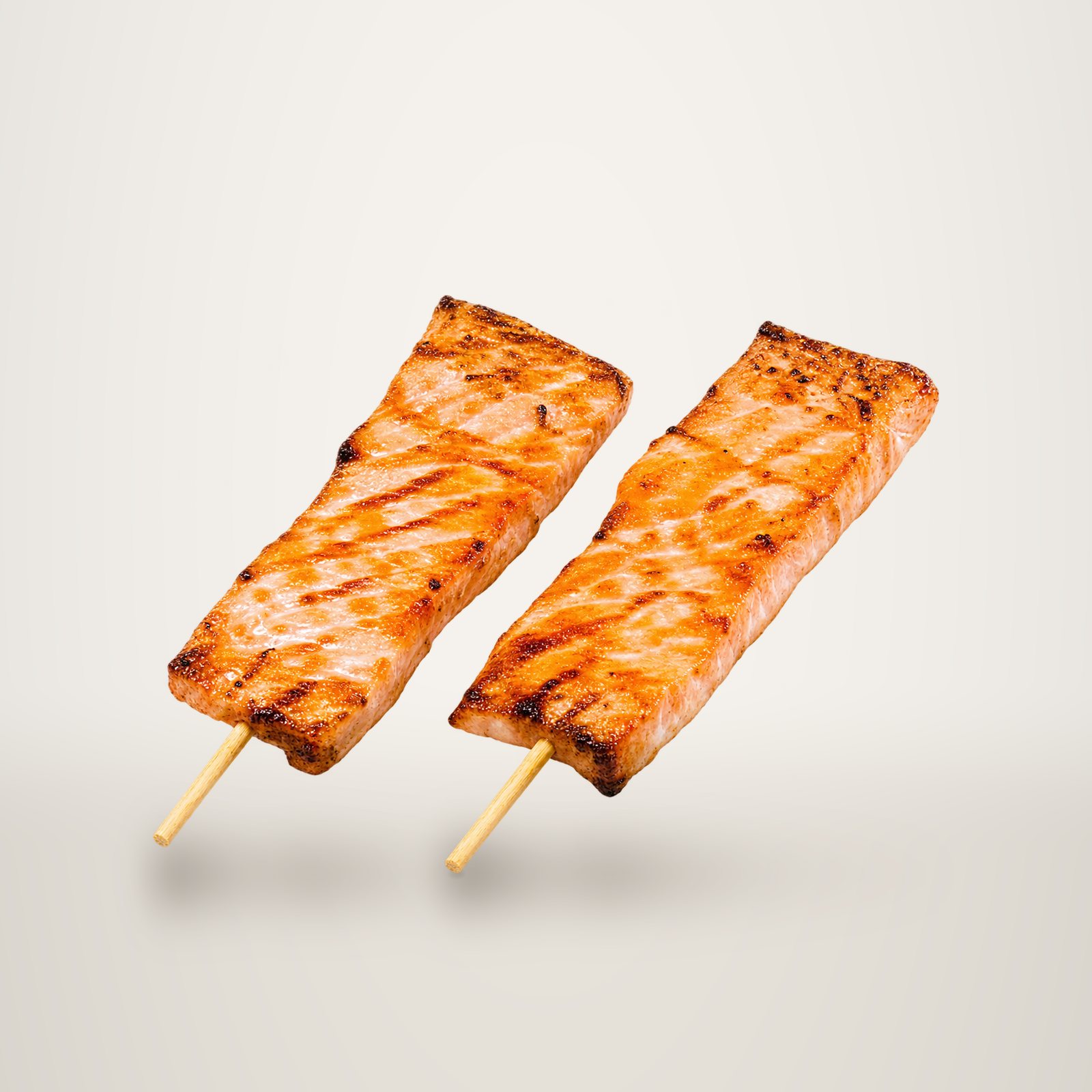 Deux brochettes de saumon grillé et laqué posées côte à côte sur un fond blanc uni.