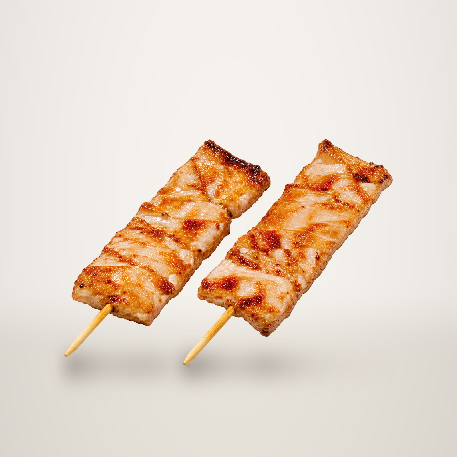 Deux brochettes de poulet grillé et glacé, posées côte à côte sur un fond blanc uni.