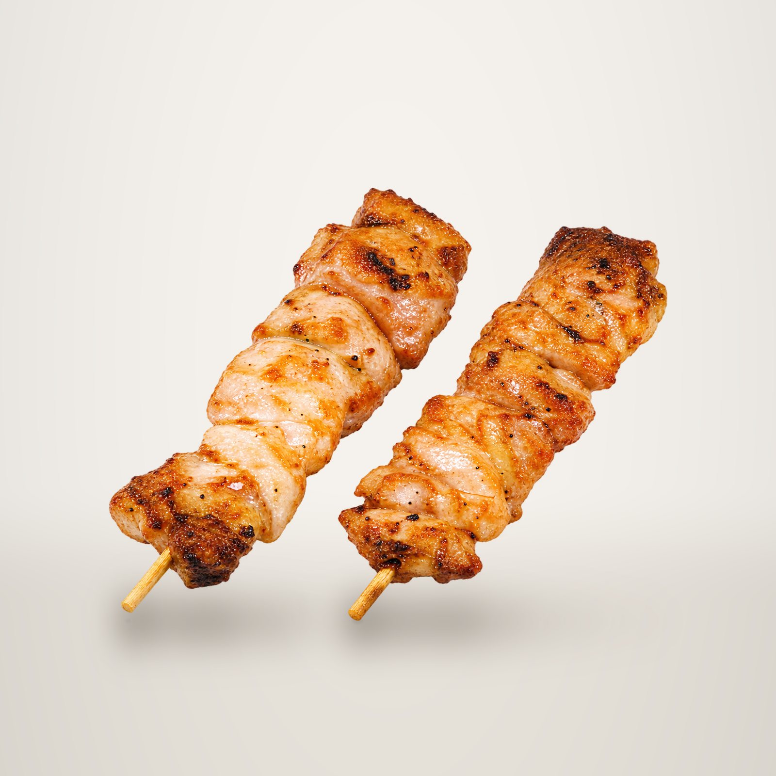 Deux brochettes de viande marinée et grillée, présentées côte à côte sur un fond blanc uni.