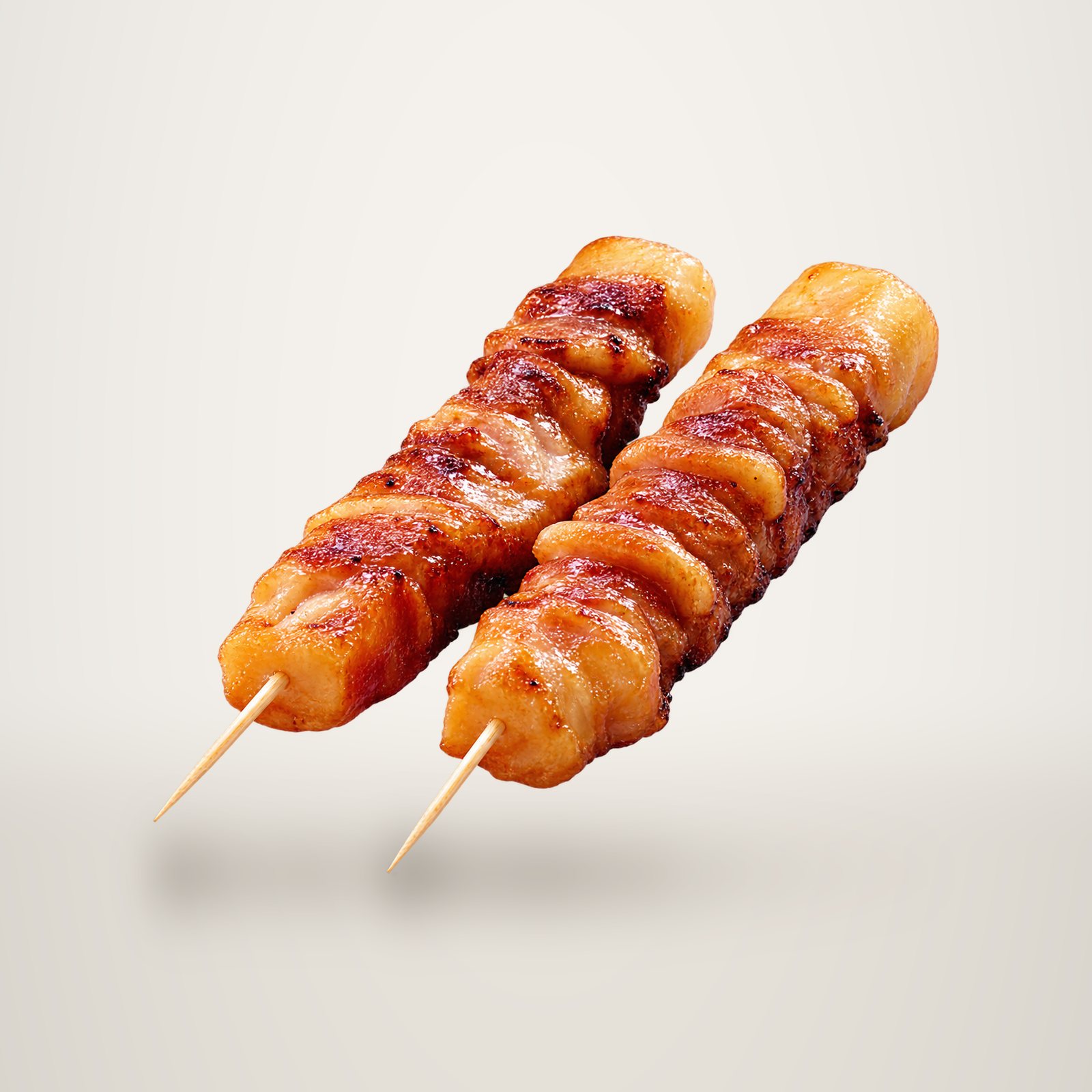 Deux brochettes de viande grillée et glacée, posées côte à côte sur un fond blanc uni.