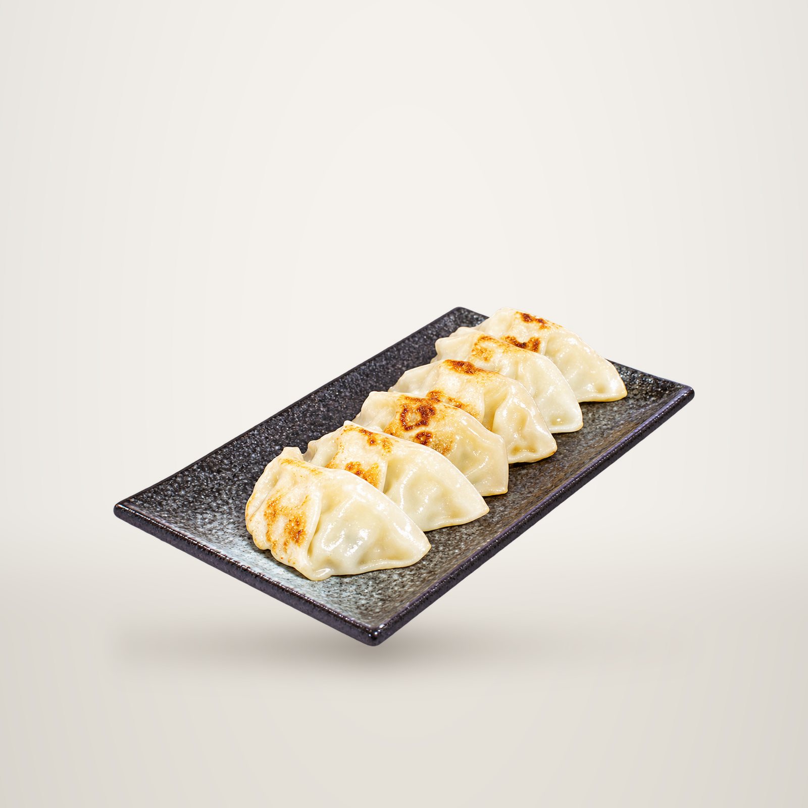 Cinq gyozas grillés et dorés disposés sur un plateau rectangulaire noir texturé, posé sur un fond blanc uni.