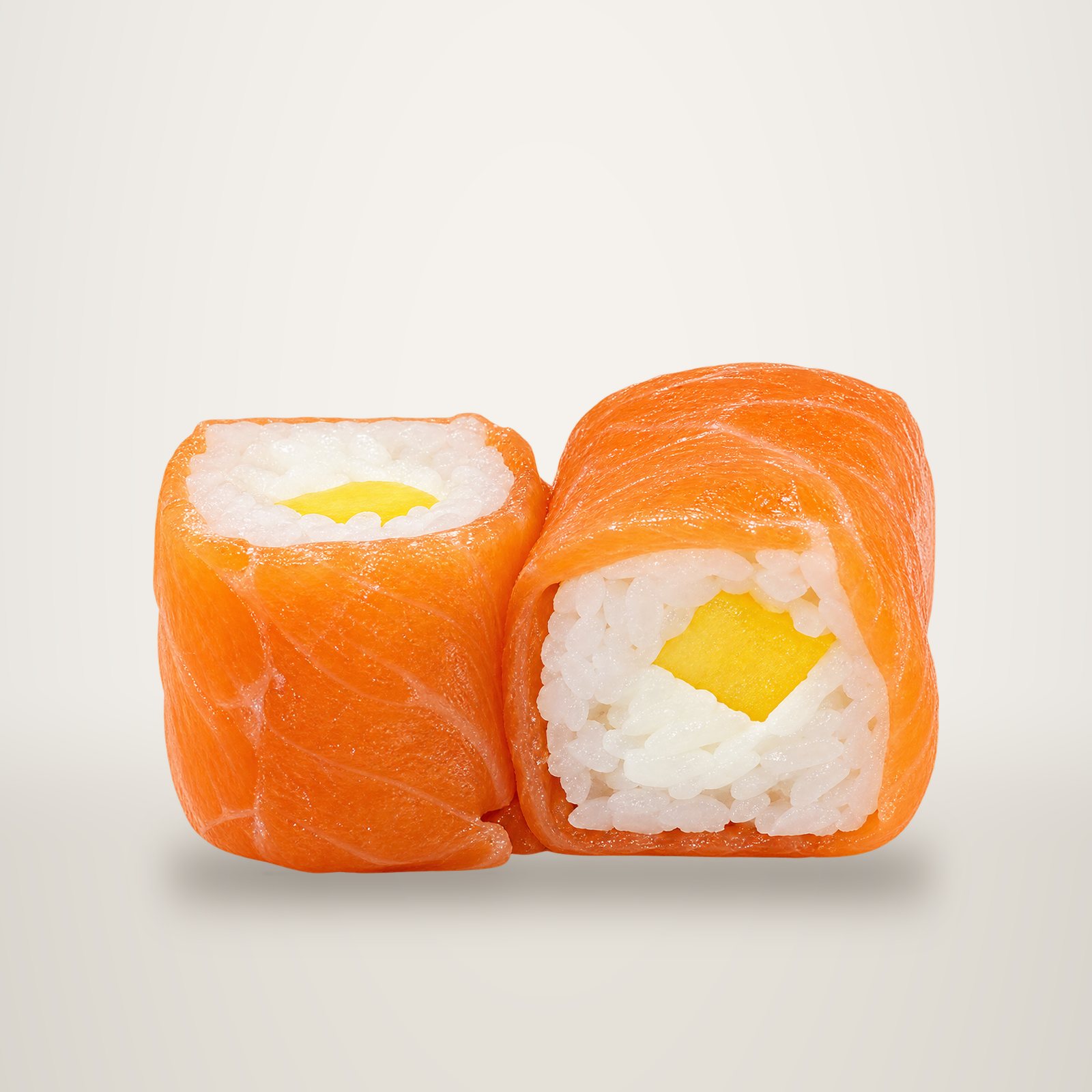 Deux rouleaux de maki enveloppés de saumon, garnis de fromage frais et de morceaux de mangue, sur fond blanc.