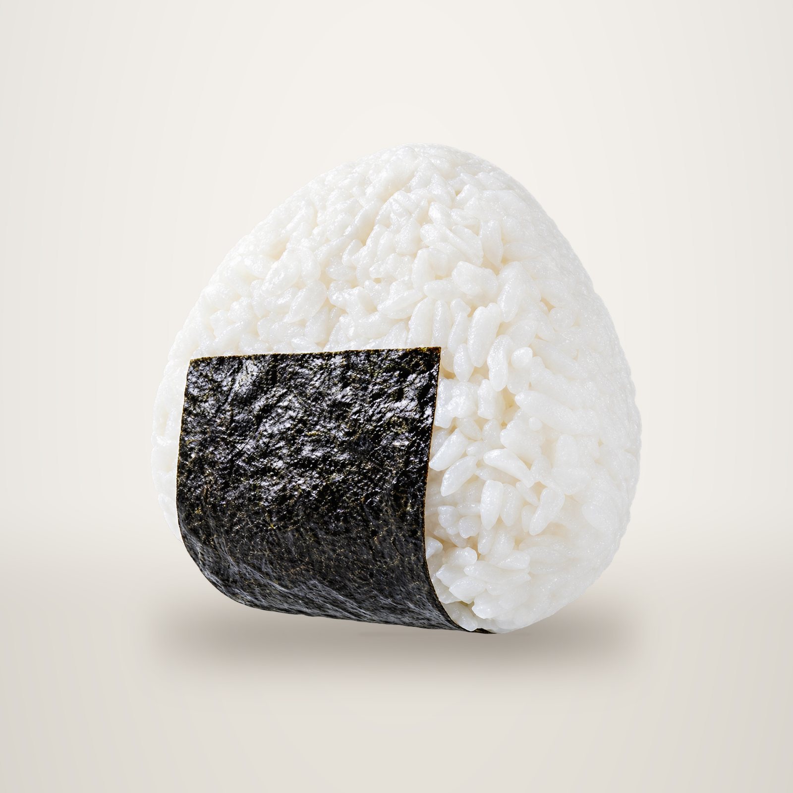 Un onigiri en forme de triangle, fait de riz blanc et entouré d'une bande d'algue nori, photographié sur fond blanc uni.
