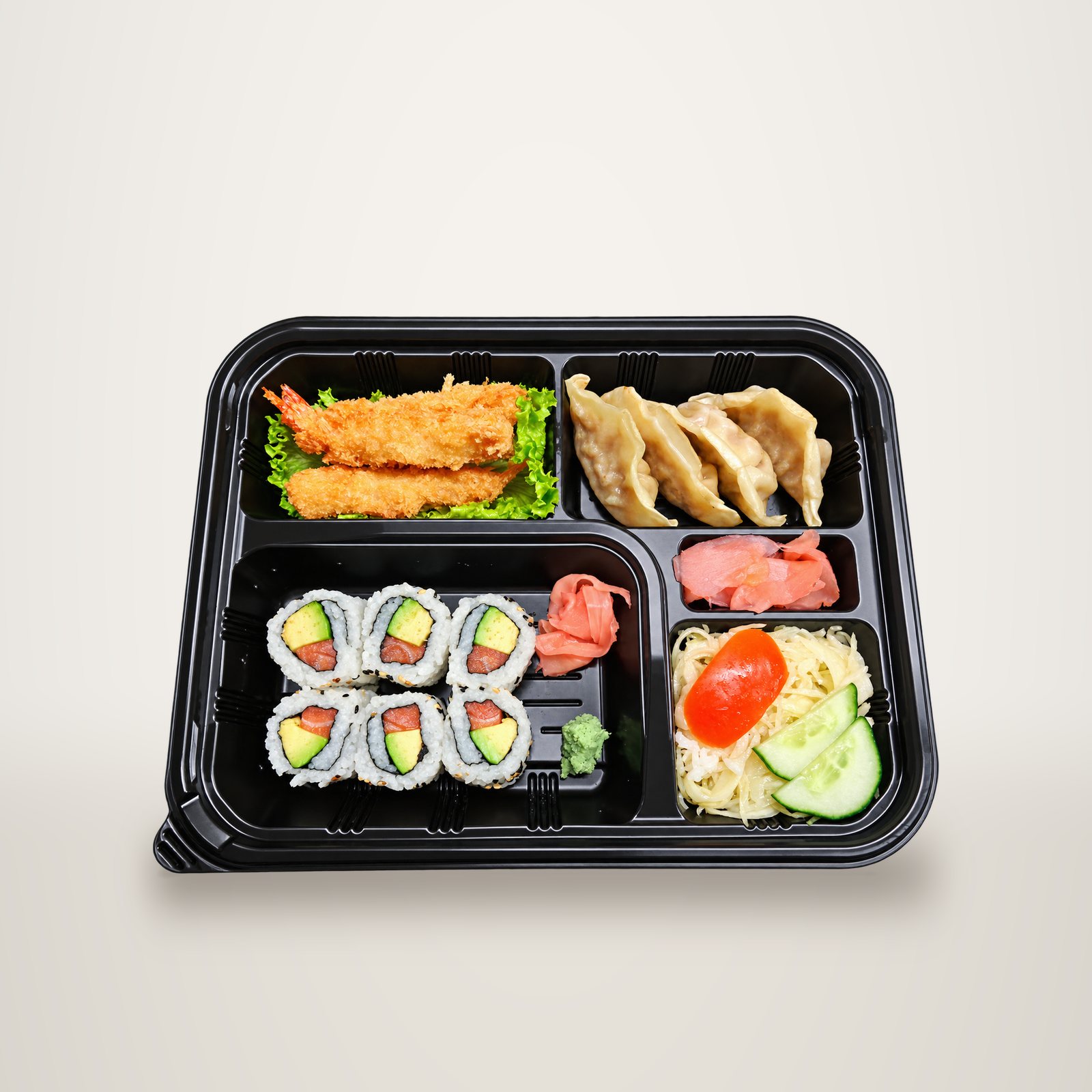 Vue de dessus d'un plateau bento noir contenant des makis saumon avocat, des crevettes frites, des raviolis gyoza, du gingembre, du wasabi et une salade.