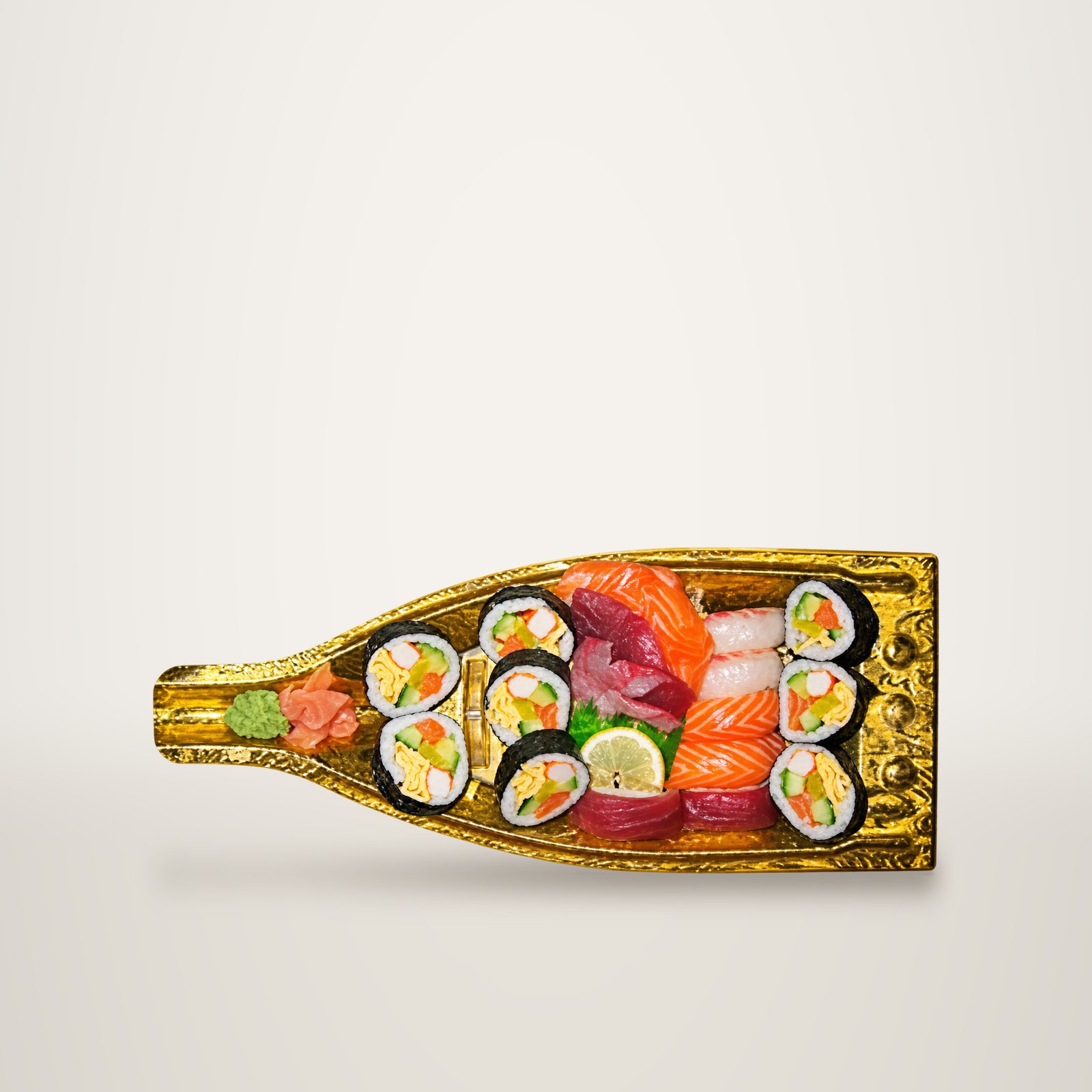 Un plateau doré en forme de bateau garni de makis, de sashimis de saumon et de thon, de gingembre et de wasabi.