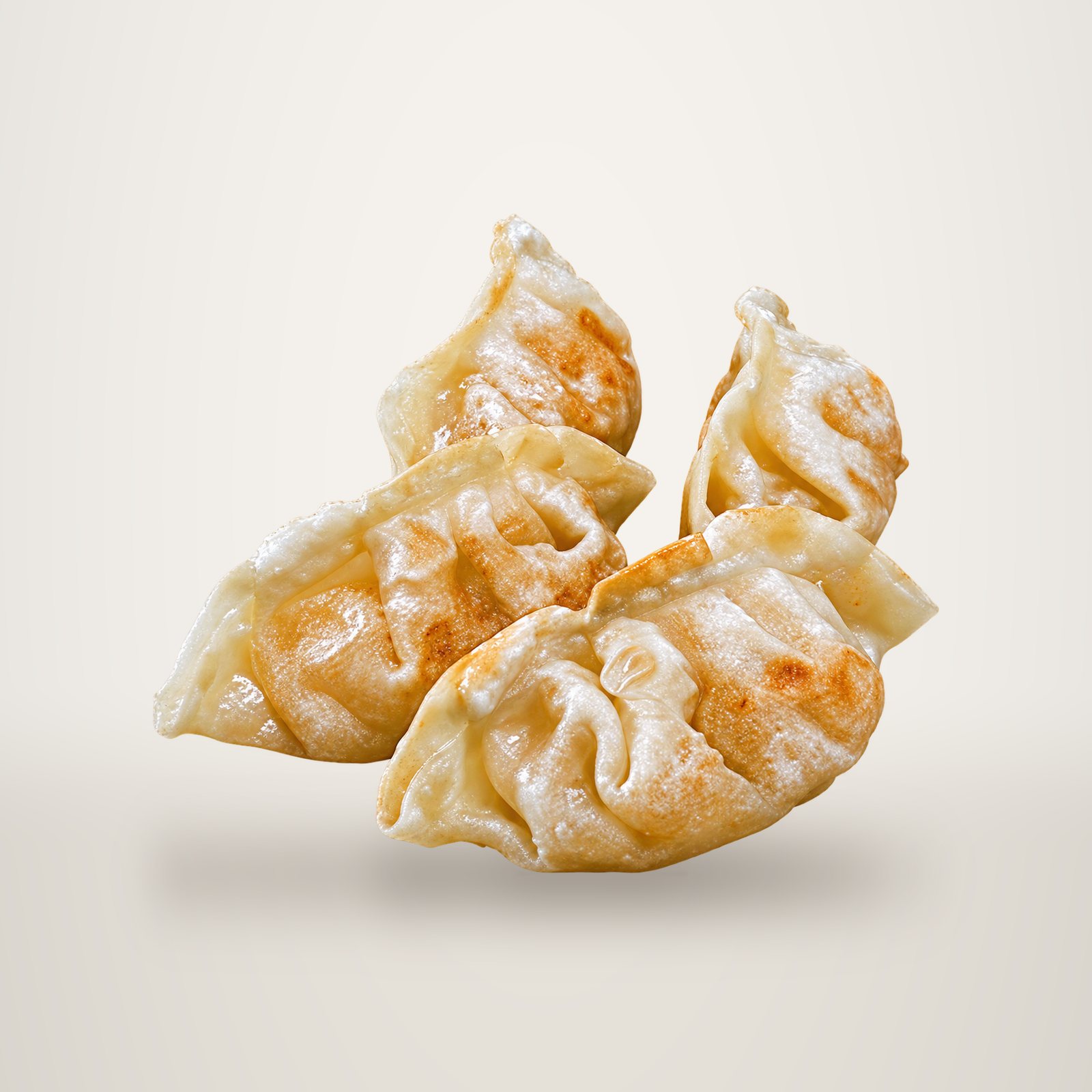 Quatre raviolis asiatiques grillés à la pâte plissée et dorée, posés ensemble sur un fond blanc.